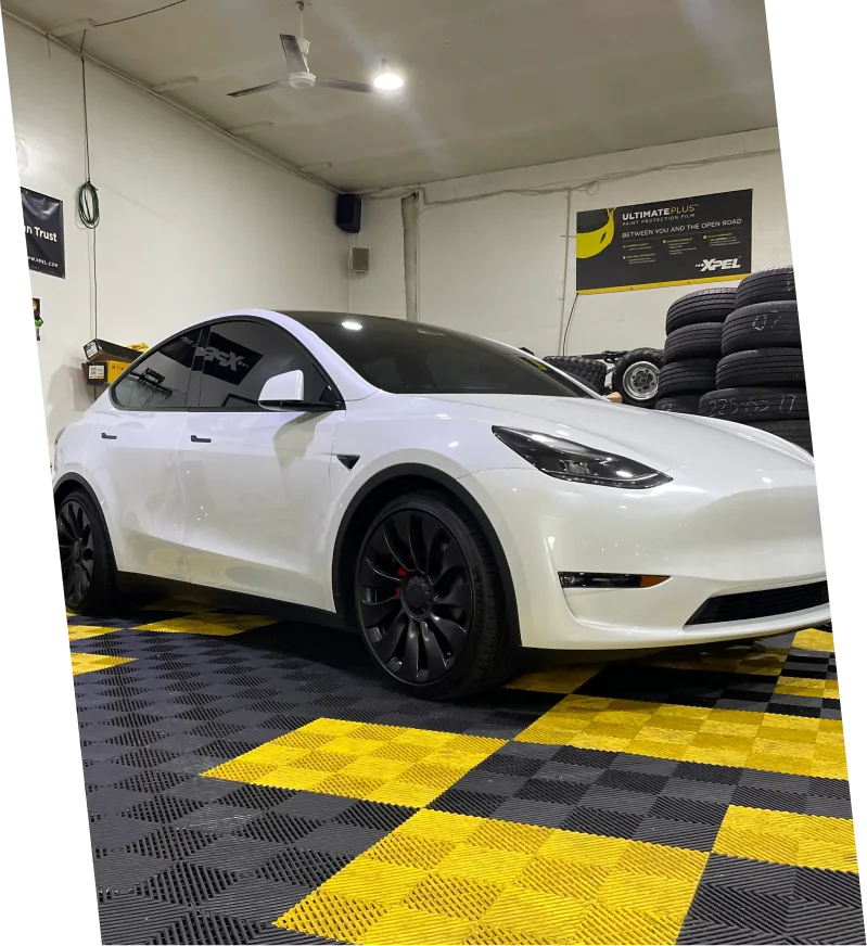 A freshly tinted Tesla Model Y parked inside Brandon's Window Tinting shop