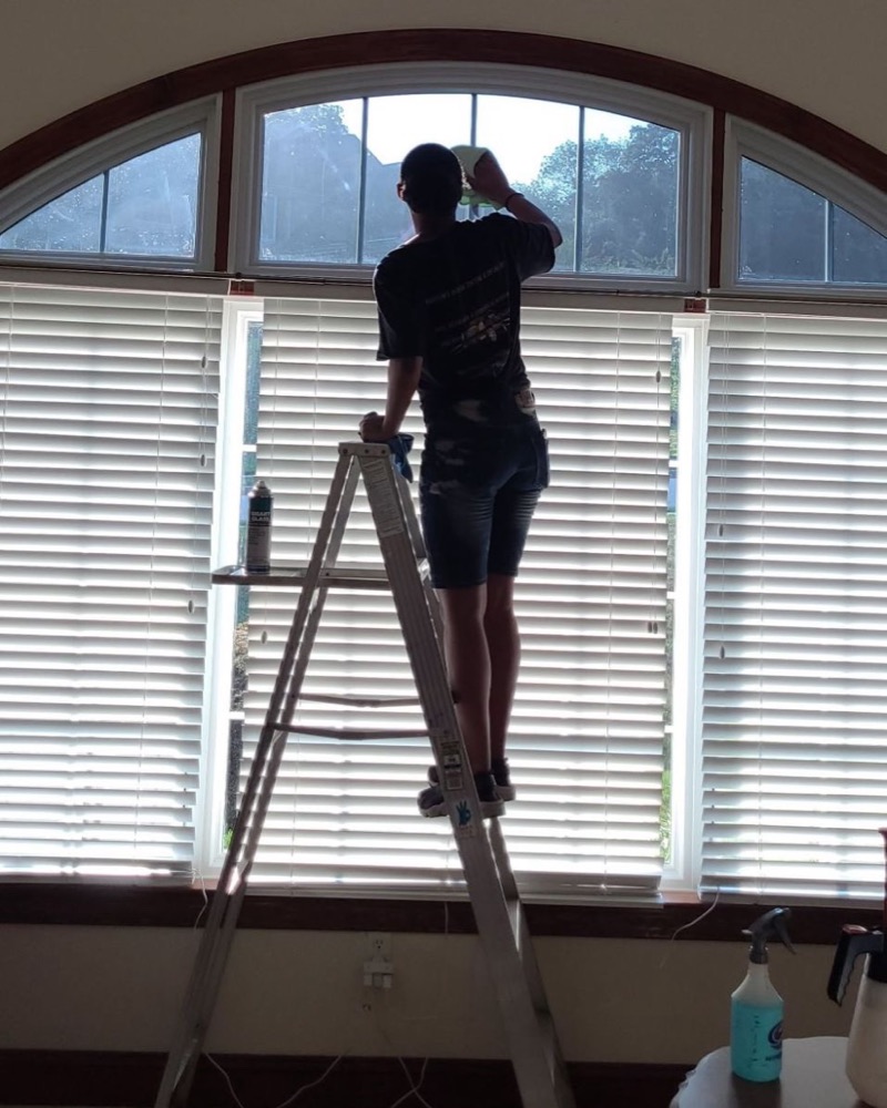 Installer applying window film to an arched window from a ladder